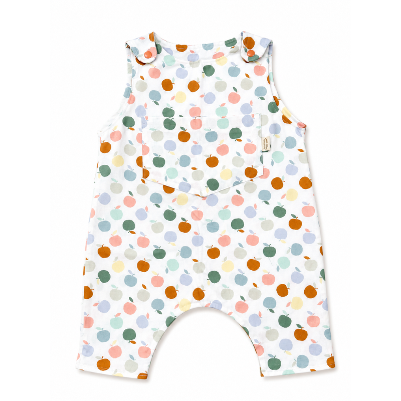 A sleeveless baby romper with a colorful apple print on a white background, featuring ruffled shoulder straps and a small side tag.