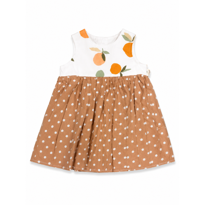 A sleeveless baby dress with a white bodice featuring an orange and green citrus fruit print, and a pleated brown skirt with white polka dots.
